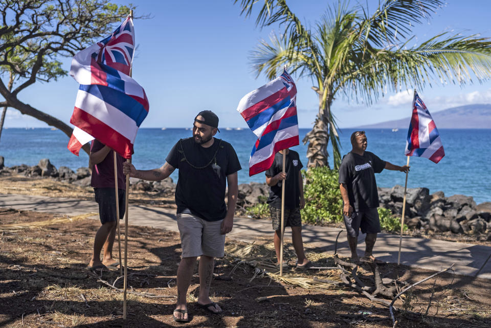 Community members hold Hawaiian flags during a news conference with Lahaina, Hawaii, residents affected by a deadly wildfire in Lahaina, Hawaii, Friday, Aug. 18, 2023. (AP Photo/Jae C. Hong)