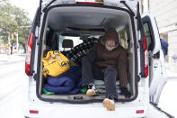 A man climbs out of a van as he is moved to a warming shelter at Travis Park Methodist Church to help escape sub-freezing temperatures, Tuesday, Feb. 16, 2021, in San Antonio. (AP Photo/Eric Gay)