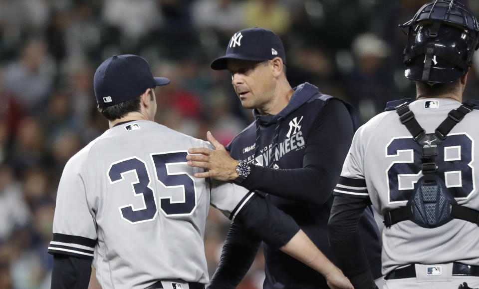 New York Yankees manager Aaron Boone, center, sends off relief pitcher Cory Gearrin (35) during a baseball game against the Seattle Mariners Monday, Aug. 26, 2019, in Seattle. (AP Photo/Elaine Thompson)
