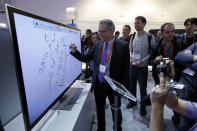 Moti Elmaliach, center, of Israel, writes on a display using Panasonic's electronic touch pen at the Panasonic booth at the International Consumer Electronics Show.