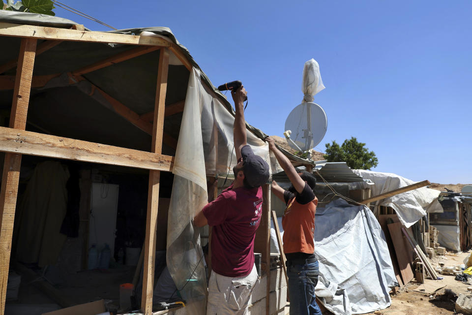 In this Sunday, June 16, 2019 photo, Syrian refugees remove the tarp covering of their wooden tent in a refugee camp in the eastern Lebanese border town of Arsal, Lebanon. Authorities in Lebanon are waging their most aggressive campaign yet against Syrian refugees, making heated calls for them to go back to their country and taking action to ensure they can’t put down roots. They are shutting down shops where Syrians work without permits and ordering the demolition of anything in their squalid camps that could be a permanent home. (AP Photo/Bilal Hussein)