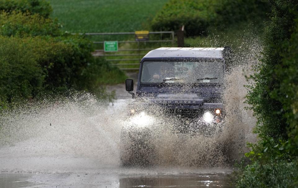 A car drives through a flooded road near Chesham, Buckinghamshire (PA)