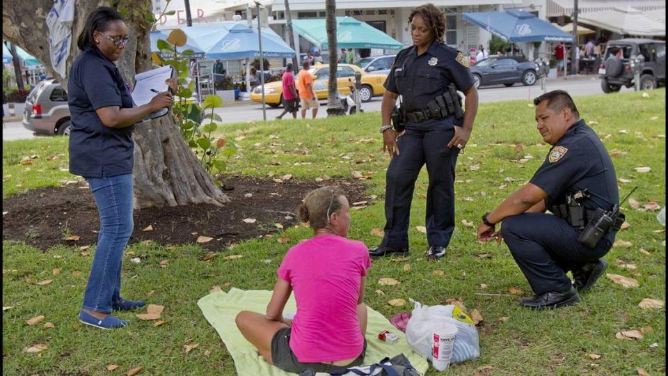 Miami Beach police officers talk with a homeless woman in Lummus Park in South Beach in 2013.