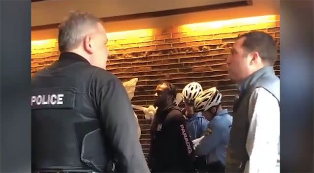 A man is questioning an officer as the two men are being escorted from the business. Source: @missydepino/ Twitter