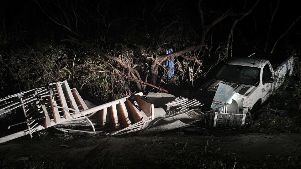 A spiral staircase lies in the brush next to a white pickup truck.