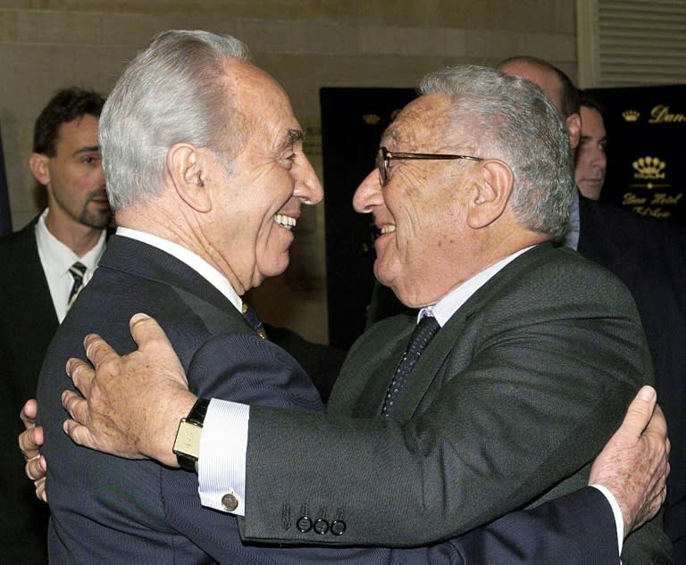 Former US secretary of state Henry Kissinger (R) receives a warm hug from former Israeli prime minister Shimon Peres in Tel Aviv in 1999