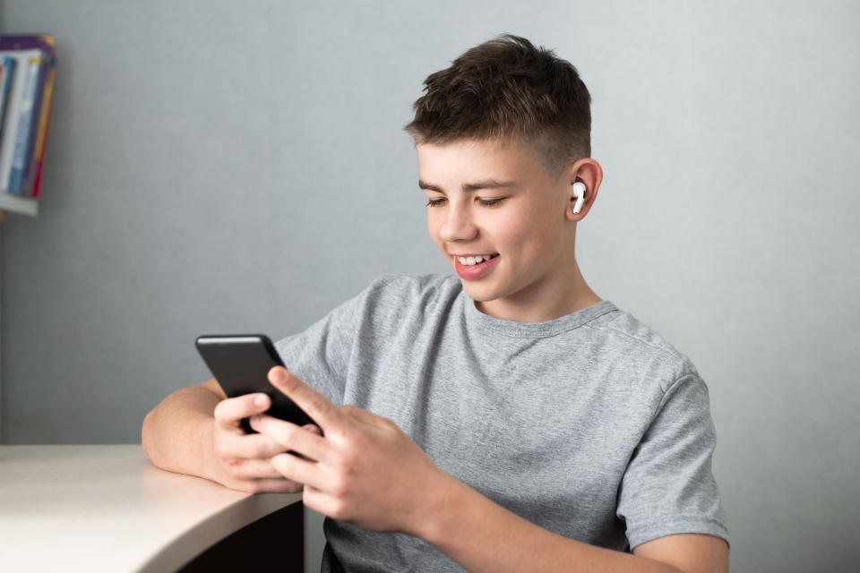 boy student teenager in headphones sitting at home, using social media