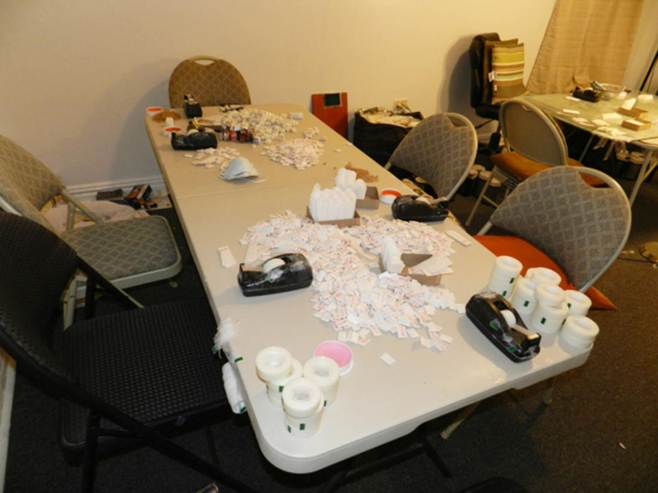 In this Jan. 30, 2014 photo provided by New York City's Office of the Special Narcotics Prosecutor, a table with packaging materials for distribution of heroin is located in a Bronx apartment during a police raid of the location. According to prosecutors it was a sophisticated operation, where workers with coffee grinders and scales toiled around the clock to break down bricks of heroin into thousands of tiny, hit-sized baggies, bearing such stamped brands as "Government Shutdown" and "NFL." The death of actor Philip Seymour Hoffman has once again drawn attention to a New York City heroin trade so sophisticated that getting the drug delivered to your door is nearly as easy as ordering a pizza. (AP Photo/Office of the Special Narcotics Prosecutor)