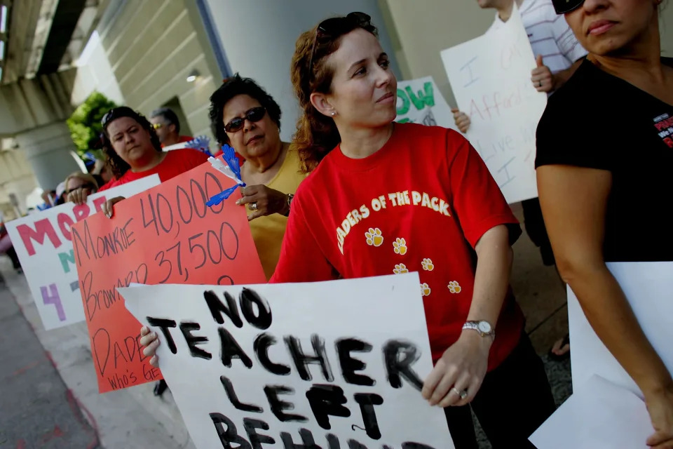 Eighth grade teacher Maria Leon holds a sign that reads: No teacher left behind.