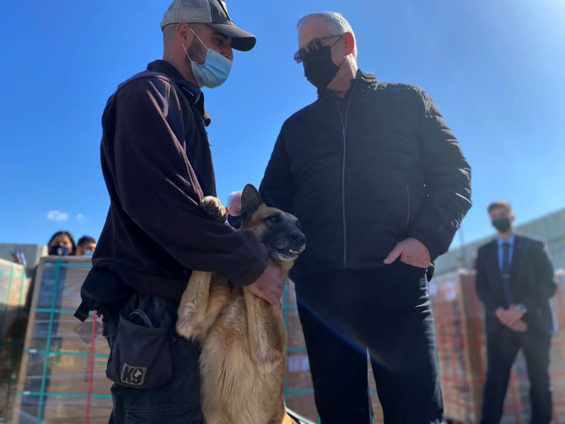 Israeli Defence Minister Benny Gantz stands next to a sniffer dog and cargo headed for the Gaza Strip during a tour of the Gaza border area, at the Kerem Shalom crossing in southern Israel