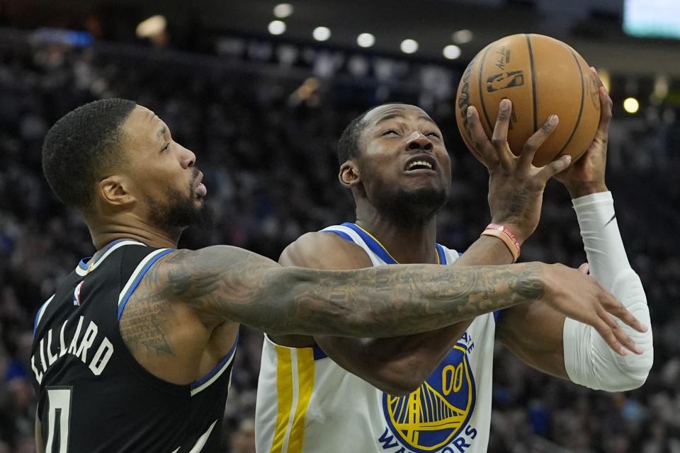 Golden State Warriors' Jonathan Kuminga is fouled by Milwaukee Bucks' Damian Lillard during the second half of an NBA basketball game Saturday, Jan. 13, 2024, in Milwaukee. The Bucks won 129-118. (AP Photo/Morry Gash)