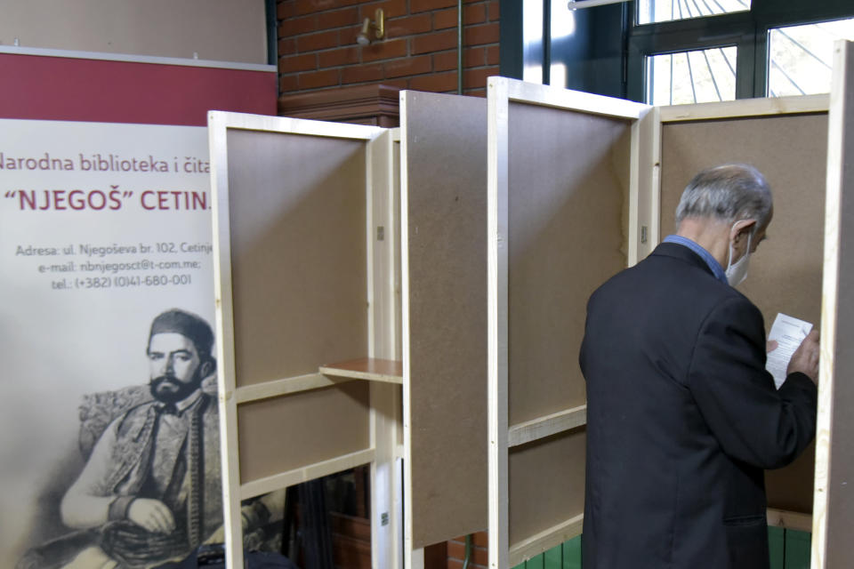 A man wearing a mask against the spread of the coronavirus prepares his ballot to vote in parliamentary elections at a polling station in Cetinje, south of Podgorica, Montenegro, Sunday, Aug. 30, 2020. Voters in Montenegro on Sunday cast ballots in a tense election that is pitting the long-ruling pro-Western party against the opposition seeking closer ties with Serbia and Russia. The parliamentary vote is marked by a dispute over a law on religious rights that is staunchly opposed by the influential Serbian Orthodox Church. (AP Photo/Risto Bozovic)