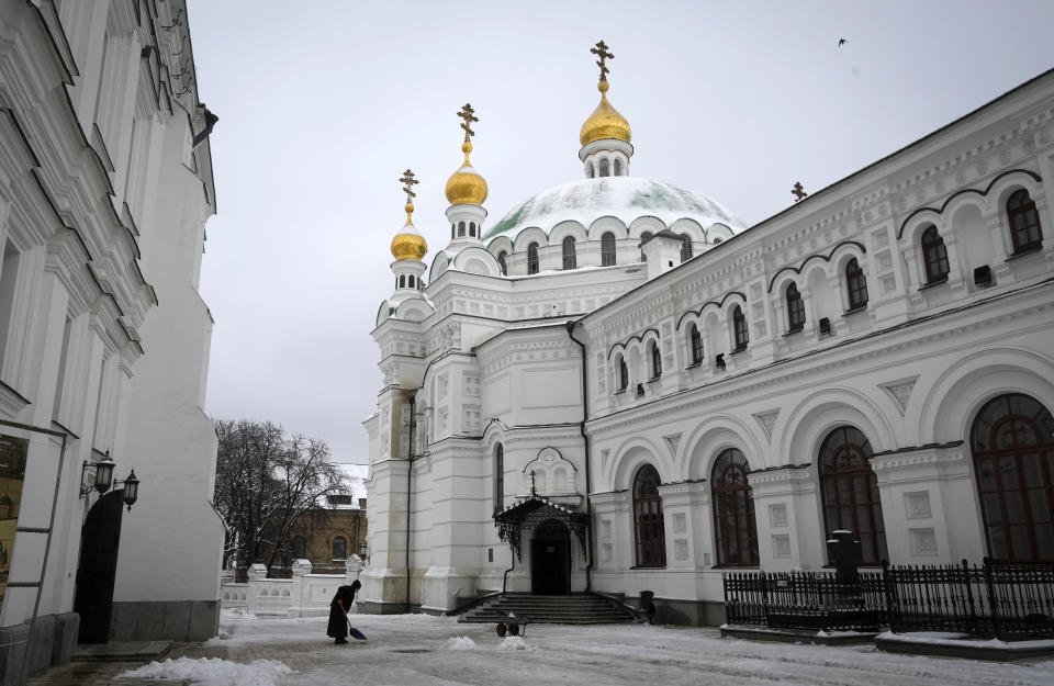 A woman cleans the snow in the Pechersk Lavra monastic complex in Kyiv, Ukraine, Tuesday, Nov. 22, 2022. Ukraine's counter-intelligence service, police officers and the country's National Guard searched one of the most famous Orthodox Christian sites in the capital, Kyiv, after a priest spoke favorably about Russia – Ukraine's invader – during a service. (AP Photo/Efrem Lukatsky)