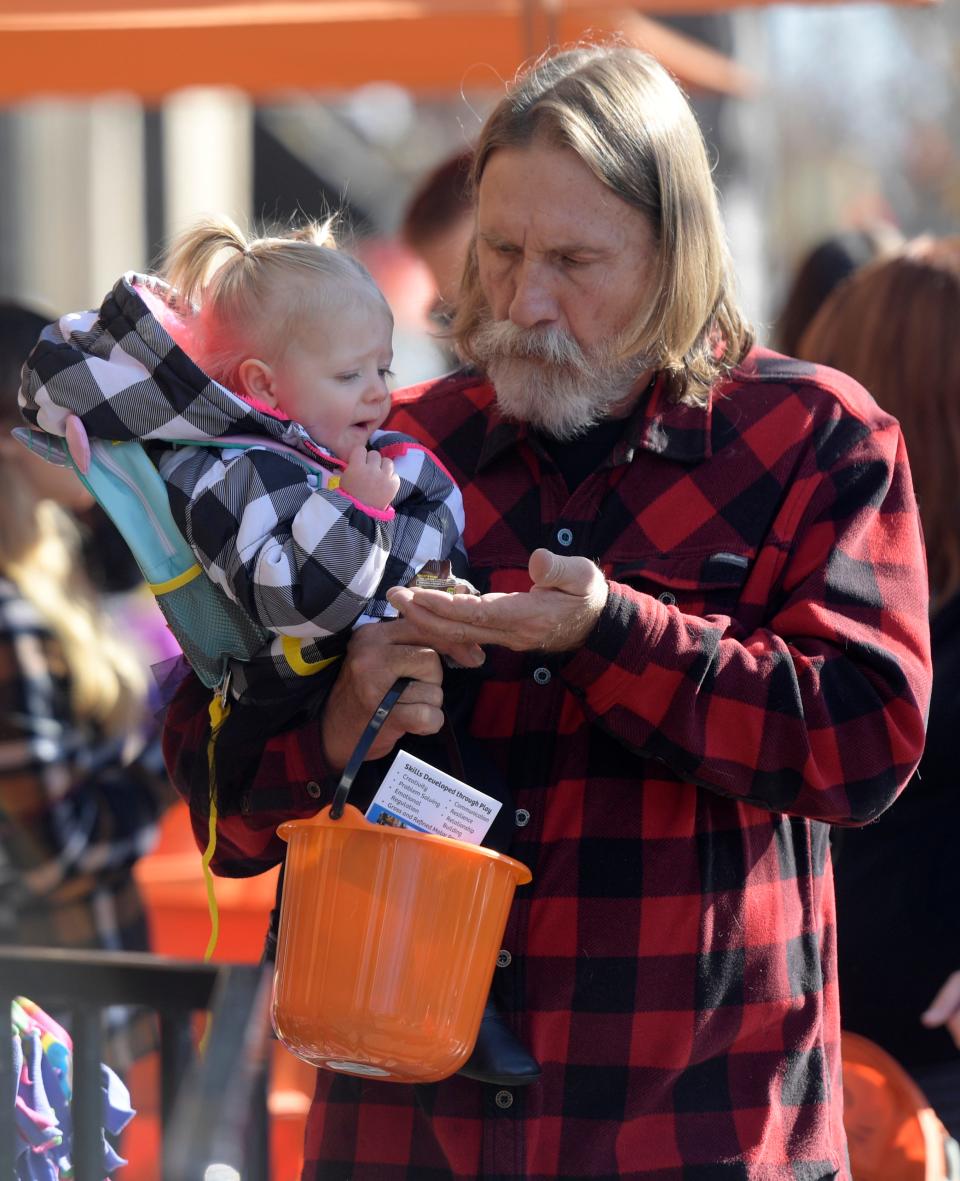 In this file photo, Mike Waldrep offers candy to his granddaughter, Arabelle Swanson, 1, during Tiny Tot Halloween in Fort Collins on Oct. 31, 2019.