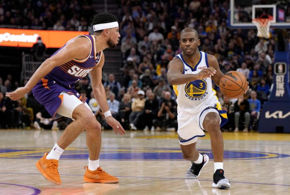 Chris Paul of the Golden State Warriors dribbles the ball while defended by Devin Booker of the Phoenix Suns during the fourth quarter of an October game at Chase Center.