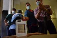 People sanitize their hands while wearing face masks as protection to prevent the spread of the coronavirus in a polling station during Basque regional election in the village of Durango, northern Spain, Sunday, July 12, 2020. (AP Photo/Alvaro Barrientos)