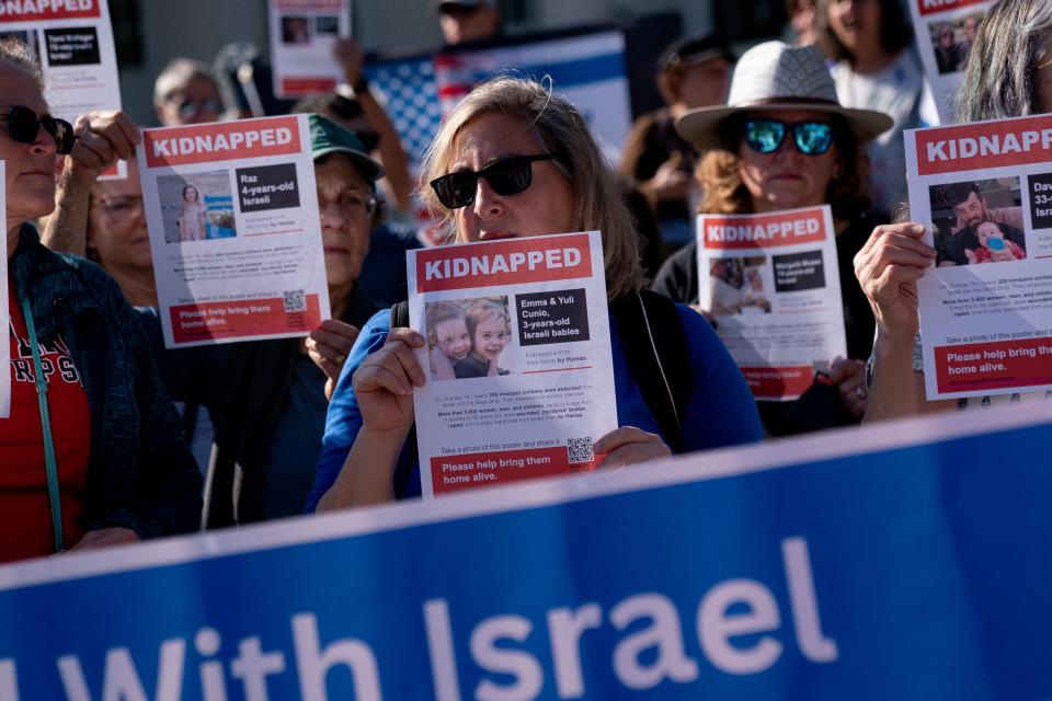 Demonstrators hold fliers, including one featuring the photo of 3-year-olds Emma and Julie Cunio, as they gather to call for the release of Israeli hostages in front of the Red Cross headquarters in Washington, DC, on November 5, 2023.