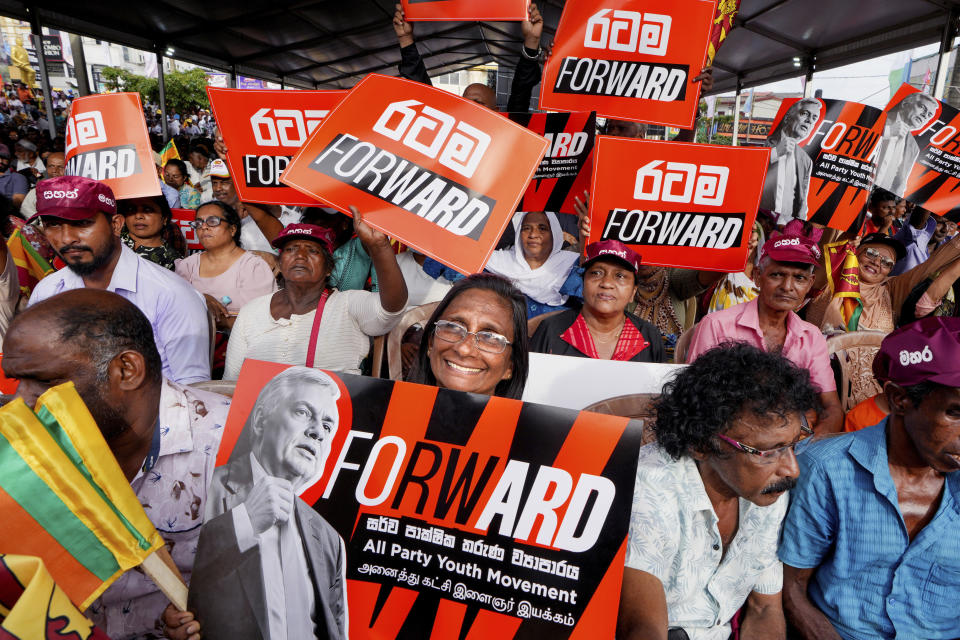 A woman supporter of Sri Lankan President and independent presidential candidate Ranil Wickremesinghe, holds a placard at an election rally in Minuwangoda, Sri Lanka, Tuesday, Sept. 17, 2024. (AP Photo/Rajesh Kumar Singh)