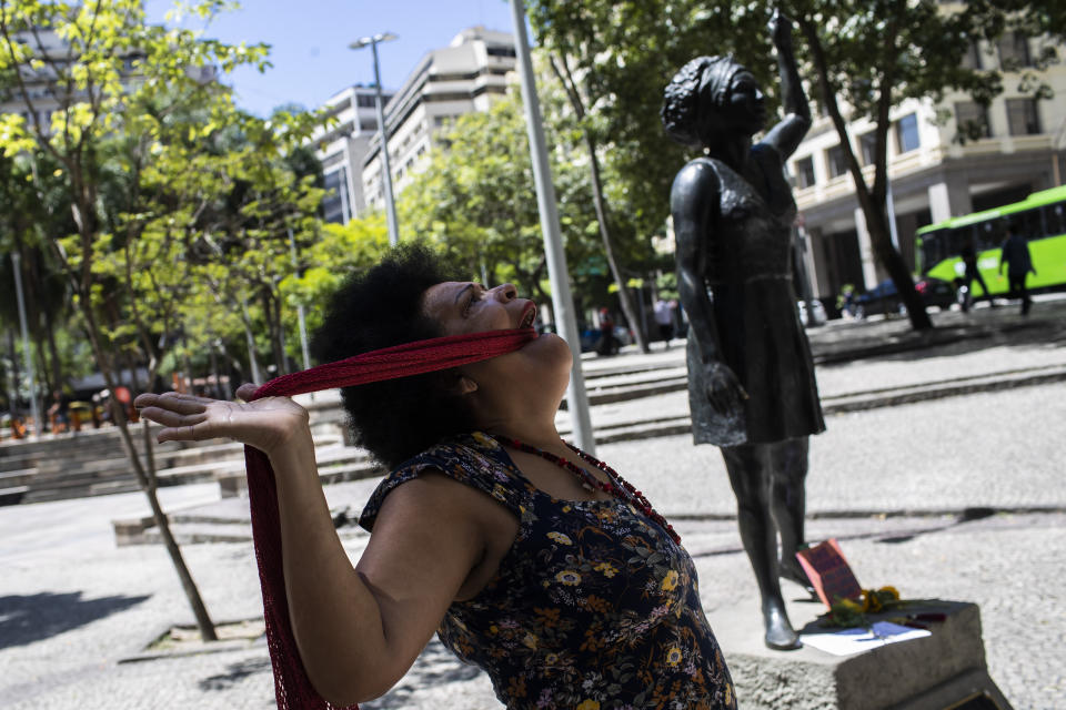 A woman acts out a performance in front of a statue of slain councilwoman Marielle Franco, to honor her and mark five years of her assassination that is still under investigation, in Rio de Janeiro, Brazil, Tuesday, March 14, 2023. (AP Photo/Bruna Prado)