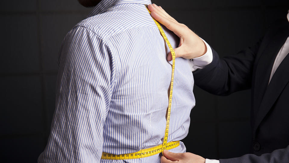 Bespoke tailor taking measurement