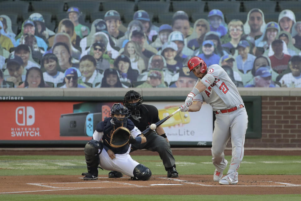 Los Angeles Angels' Mike Trout hits a solo home run during the first inning of a baseball game as Seattle Mariners catcher Austin Nola looks on, Tuesday, Aug. 4, 2020, in Seattle. (AP Photo/Ted S. Warren)