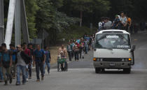 Honduran migrant Omar Orella pushes fellow migrant Nery Maldonado Tejeda in a wheelchair, as they travel with hundreds of other Honduran migrants making their way the U.S., near Chiquimula, Guatemala, Tuesday, Oct. 16, 2018. Maldonado said he lost his legs in 2015 while riding "The Beast," a northern-bound cargo train that crosses Mexico, and that this is his second attempt to reach the U.S. (AP Photo/Moises Castillo)