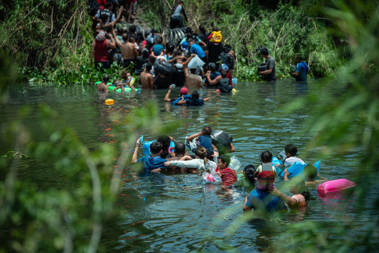 Migrantes se apresuran a subir a un lugar en la orilla norte del río Bravo antes de que miembros de la Guardia Nacional de Estados Unidos puedan instalar alambre de concertina para bloquear su acceso desde Matamoros, México, a Brownsville, Texas, el 10 de mayo de 2023. (Meridith Kohut/The New York Times)