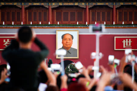 People take pictures during the flag raising ceremony on Tiananmen Square as the portrait of China's late Chairman Mao Zedong is seen in the background in Beijing, China, on the 40th anniversary of his death September 9, 2016. REUTERS/Thomas Peter