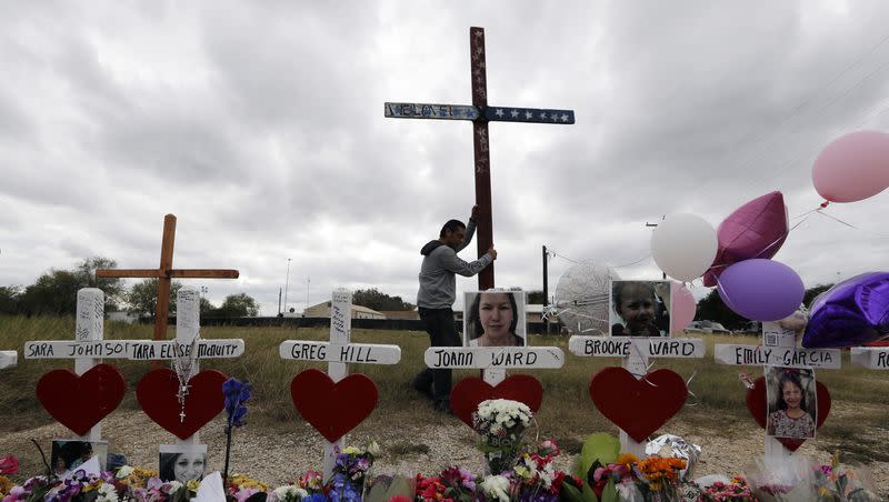 Miguel Zamora stands a cross for the victims of the Sutherland Springs First Baptist Church shooting at a makeshift memorial, Saturday, Nov. 11, 2017, in Sutherland Springs, Texas. A man opened fire inside the church in the small South Texas community, killing more than two dozen. Zamora carried the cross for three days to reach the site.