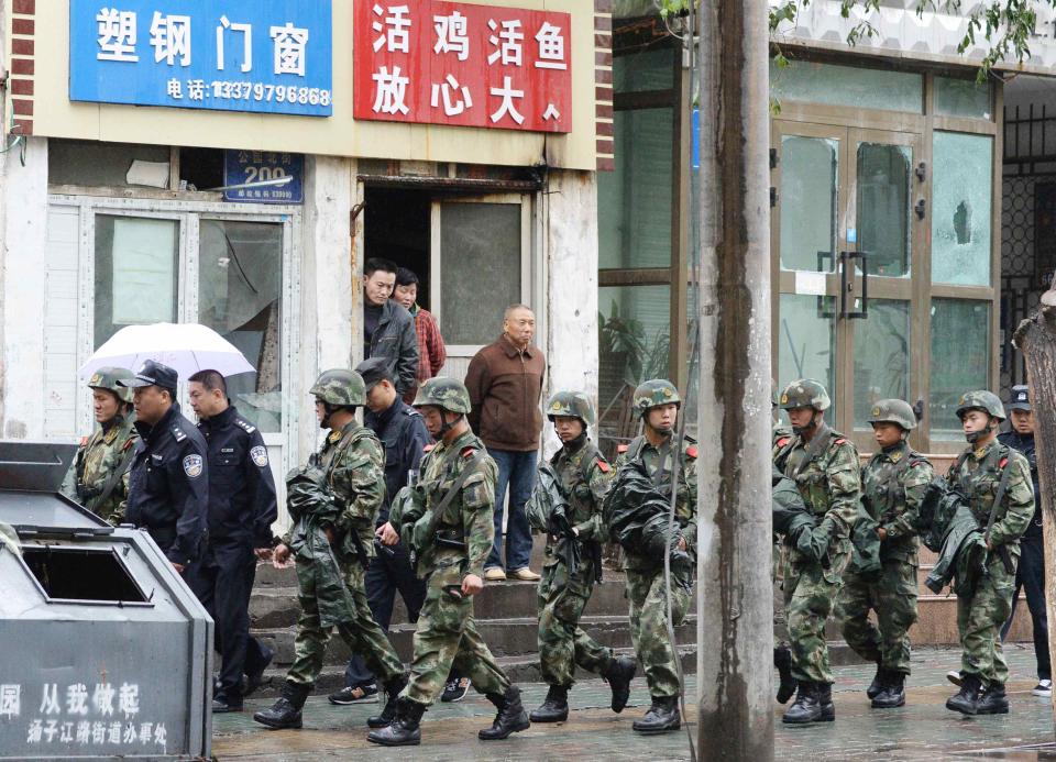 Paramilitary policemen patrol past a building with broken windows after an explosion in Urumqi, in the Xinjiang Uighur Autonomous Region, in this photo taken by Kyodo May 22, 2014. Five suicide bombers carried out the attack which killed 31 people in the capital of China's troubled Xinjiang region, state media reported a day after the deadliest terrorist attack to date in the region. Picture taken May 22, 2014. Mandatory credit REUTERS/Kyodo (CHINA - Tags: CRIME LAW POLITICS CIVIL UNREST) ATTENTION EDITORS - THIS IMAGE HAS BEEN SUPPLIED BY A THIRD PARTY. FOR EDITORIAL USE ONLY. NOT FOR SALE FOR MARKETING OR ADVERTISING CAMPAIGNS. JAPAN OUT. NO COMMERCIAL OR EDITORIAL SALES IN JAPAN. THIS PICTURE IS DISTRIBUTED EXACTLY AS RECEIVED BY REUTERS, AS A SERVICE TO CLIENTS. YES