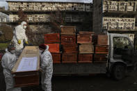 Workers collect and stack the coffins of people that have been recently cremated amid the new coronavirus pandemic, at the La Recoleta cemetery in Santiago, Chile, Sunday, June 28, 2020. The coffins are collected, destroyed, and processed by a company specialized in organic waste. (AP Photo/Esteban Felix)