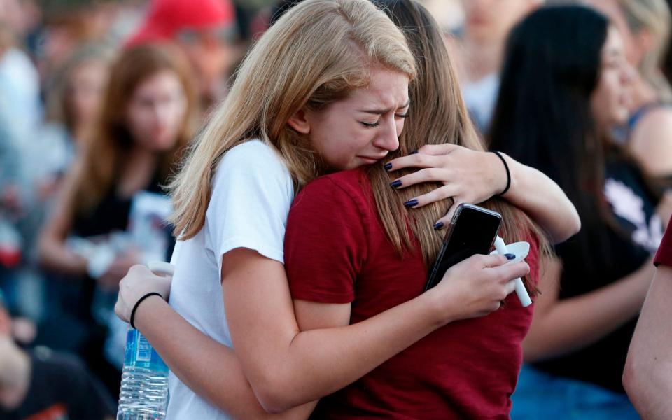 Mourners grieve as they await the start of a candlelight vigil for the victims - AFP