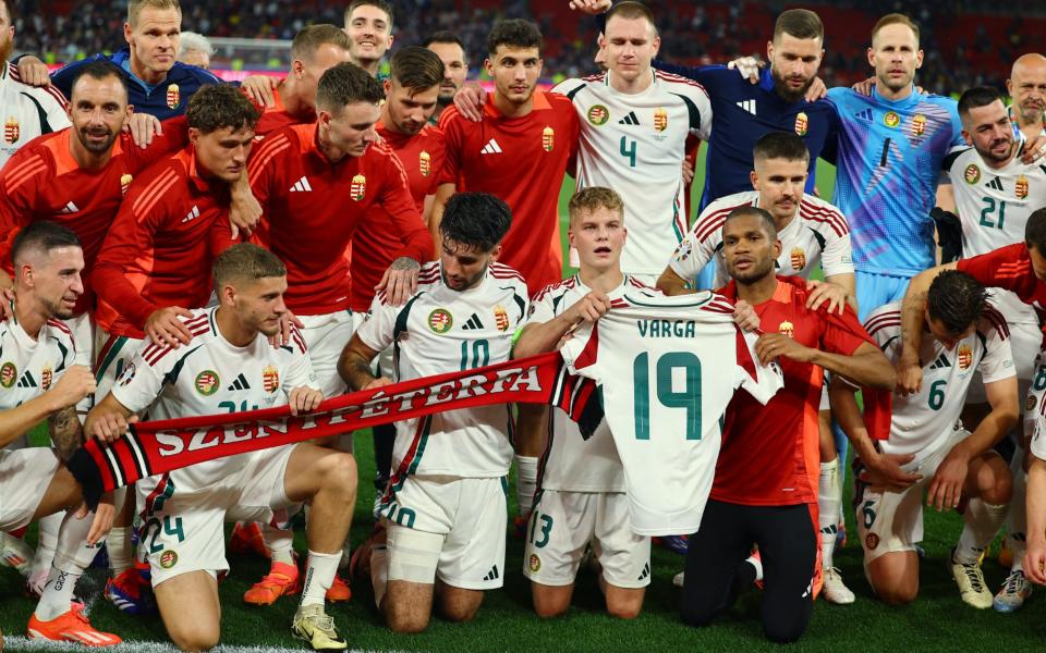 Hungary players celebrate after the match and hold up a shirt with Barnabas Varga's name after he was stretchered off