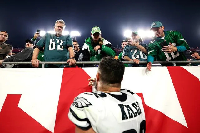 <p>Kevin Sabitus/Getty Images</p> Jason Kelce talks with his family in the stands after an NFL wild-card playoff football game in January 2024.