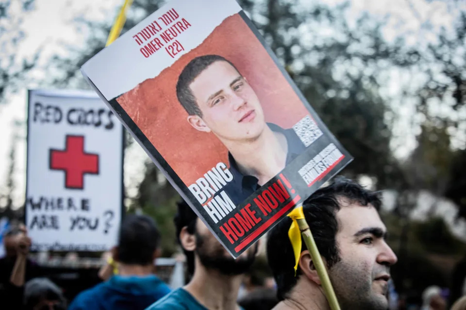 A man holds a photo of Omer Neutra during a rally calling for the release of hostages. 