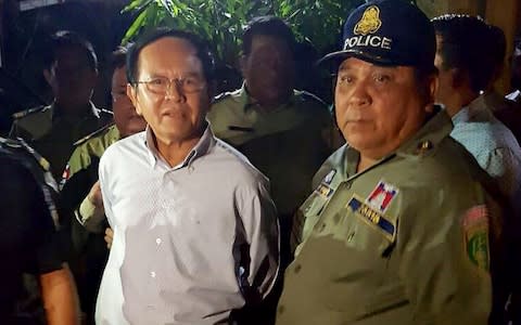 Cambodian opposition leader Kem Sokha (L) is escorted by police at his home in Phnom Penh  - Credit: AFP