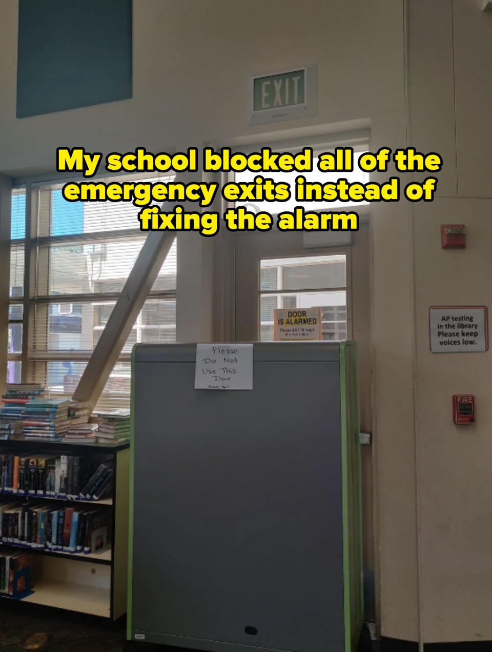 Library door with a sign warning "Please Do Not Use This Door" and another cautioning "DOOR IS ALARMED." Bookshelves and an exit sign are visible