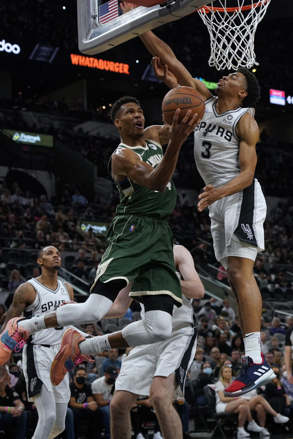 Milwaukee Bucks' Giannis Antetokounmpo, front left, drives against San Antonio Spurs' Keldon Johnson (3) during the second half of an NBA basketball in San Antonio, Texas, Saturday, Oct. 23, 2021. (AP Photo/Chuck Burton)