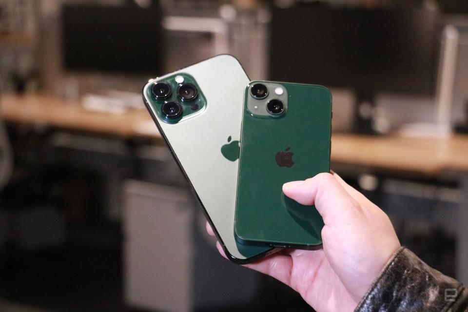 <p>A green iPhone 13 and an "Alpine green" iPhone 13 Pro Max stacked diagonally atop each other, held in mid-air.</p>
