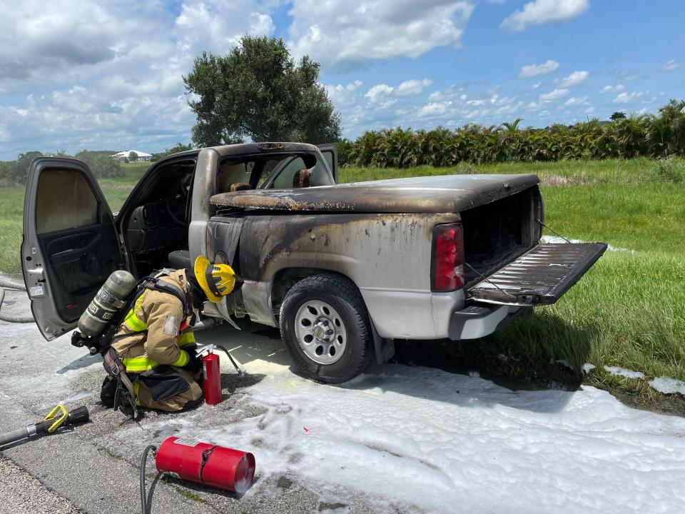 A firefighter kneels next to a pickup that was engulfed in flames on I95 near Palm City August 3, 2023.