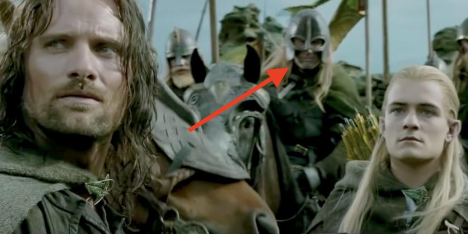 Two men — Aragorn (Viggo Mortensen) and Legolas (Orlando Bloom) — stand in front of many armored people on horseback.