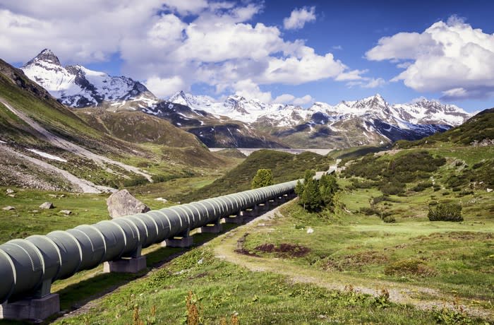 A pipeline with a snow covered mountain in the background.