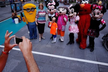Costumed characters take photographs with tourists in Times Square while staying within new zones designated for street performers to solicit tips for their services in New York, U.S. on June 21, 2016. REUTERS/Lucas Jackson/File Photo