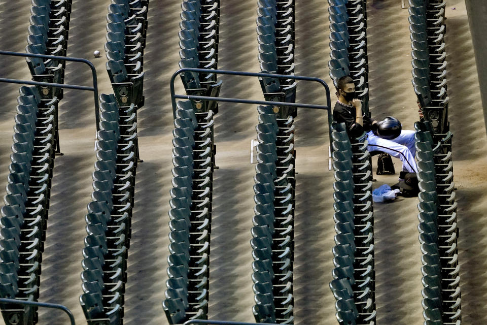 A lone foul ball sits in an aisle as an Arizona Diamondbacks ballboy watches from the stands during the sixth inning of a baseball game against the San Diego Padres Saturday, Aug. 15, 2020, in Phoenix. (AP Photo/Matt York)