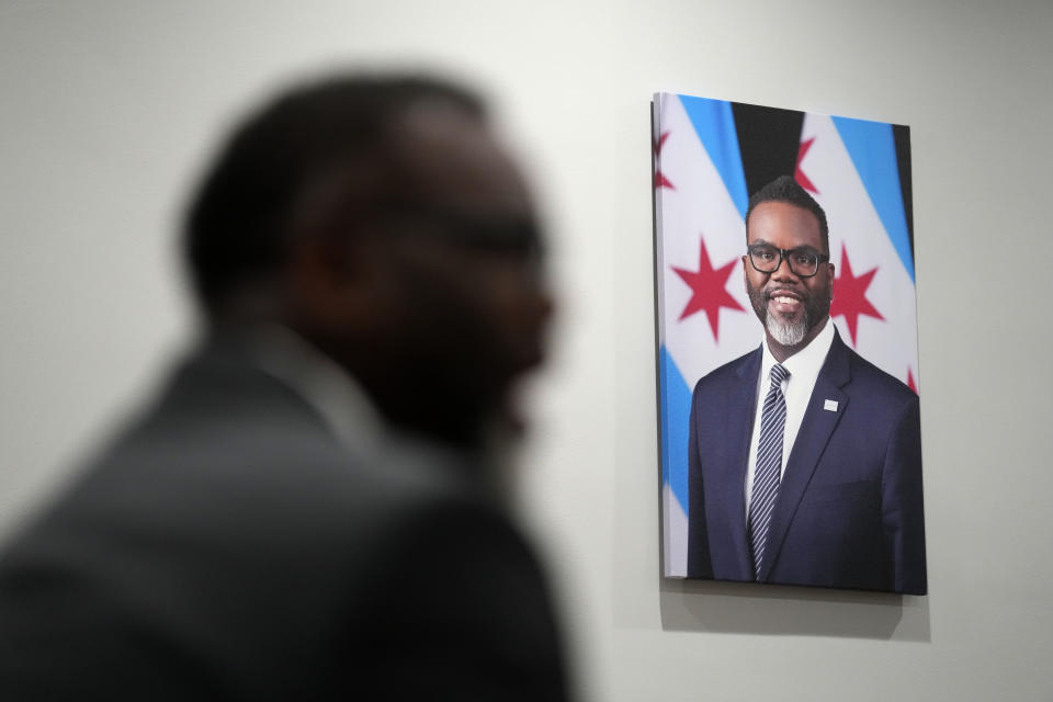 With his official portrait hanging on the wall, Chicago Mayor Brandon Johnson responds to a question in his City Hall office during an interview with The Associated Press Monday, May 6, 2024, in Chicago. The rookie mayor's bumpy first year has been a test of his progressive credentials. He's navigated an evolving migrant crisis, budget gaps, persistent crime and a troubled transit system to name a few. While there have been wins for workers and social services, he's struggled with businesses, police and fellow Democrats. (AP Photo/Charles Rex Arbogast)