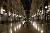 A cleaner sweeps in an empty Vittorio Emanuele II arcarde, in Milan, northern Italy, early Sunday, Oct. 25, 2020. Since the 11 p.m.-5 a.m. curfew took effect last Thursday, people can only move around during those hours for reasons of work, health or necessity. (AP Photo/Luca Bruno)