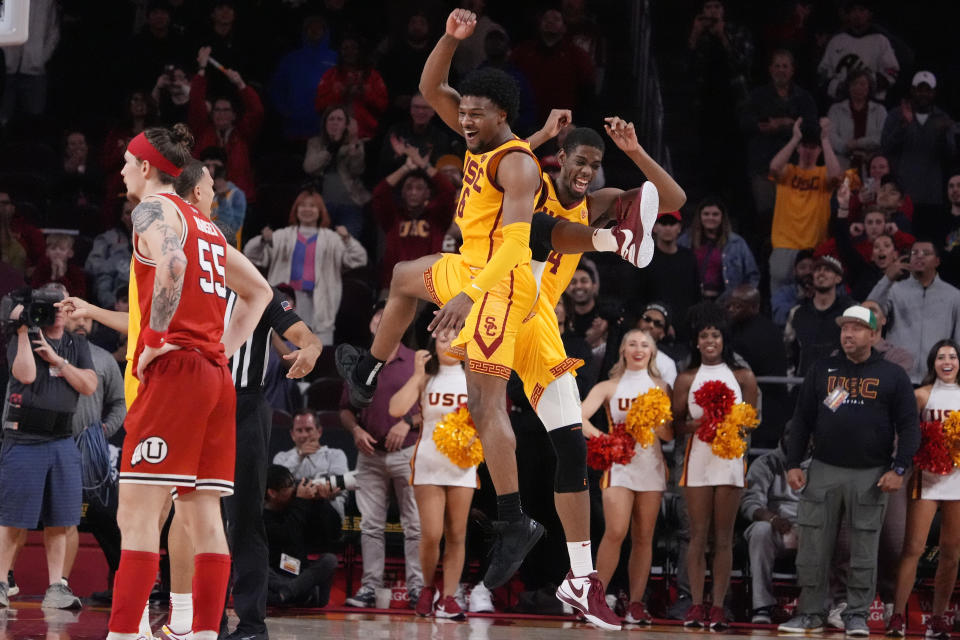 Southern California guard Bronny James, center, and forward Joshua Morgan, right, celebrate after forward DJ Rodman scored with seconds left, while Utah guard Gabe Madsen, left, stands by during the second half of an NCAA college basketball game Thursday, Feb. 15, 2024, in Los Angeles. (AP Photo/Mark J. Terrill)