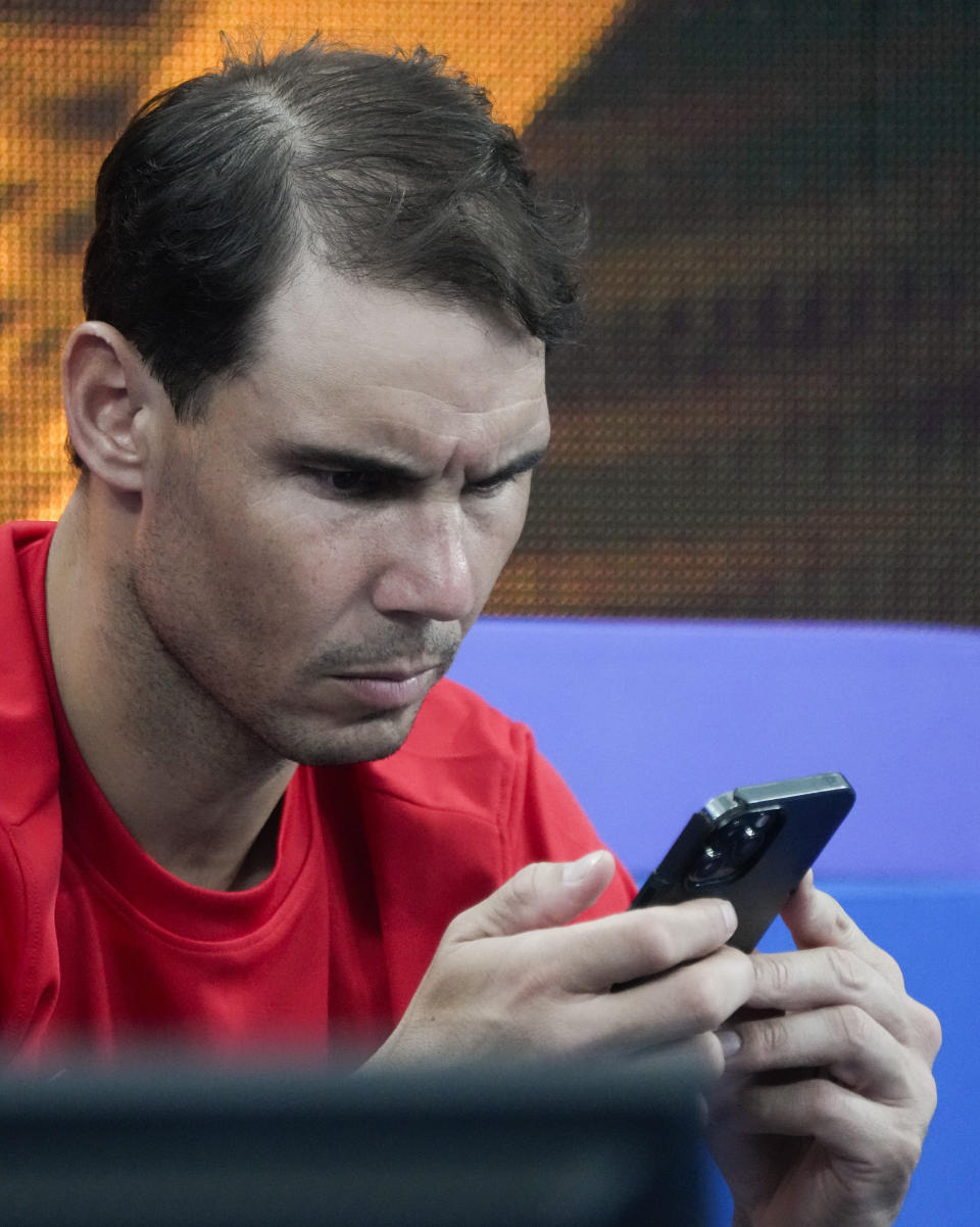 Spain's Rafael Nadal looks at his mobile phone in the team box as compatriot Jessica Bouzas Maneiro plays Australia's Olivia Godecki in their Group D match at the United Cup tennis event in Sydney, Australia, Tuesday, Jan. 3, 2023. (AP Photo/Mark Baker)