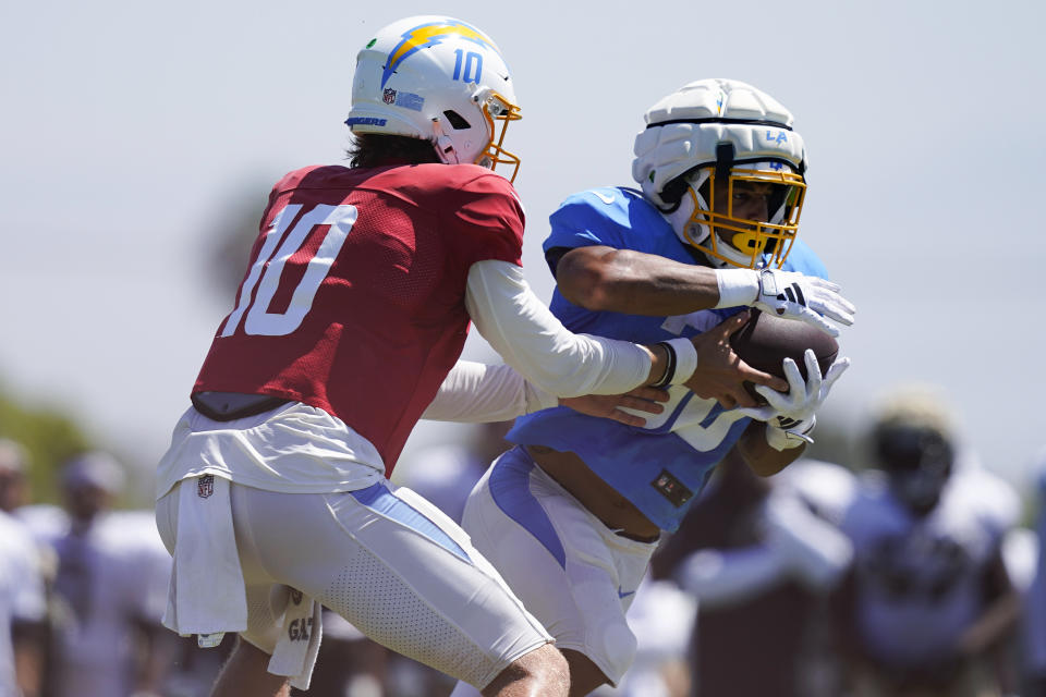 Los Angeles Chargers quarterback Justin Herbert (10) hands off the ball to running back Austin Ekeler (30) during a joint NFL football practice with the New Orleans Saints, Thursday, Aug. 17, 2023, in Costa Mesa, Calif. (AP Photo/Ryan Sun)