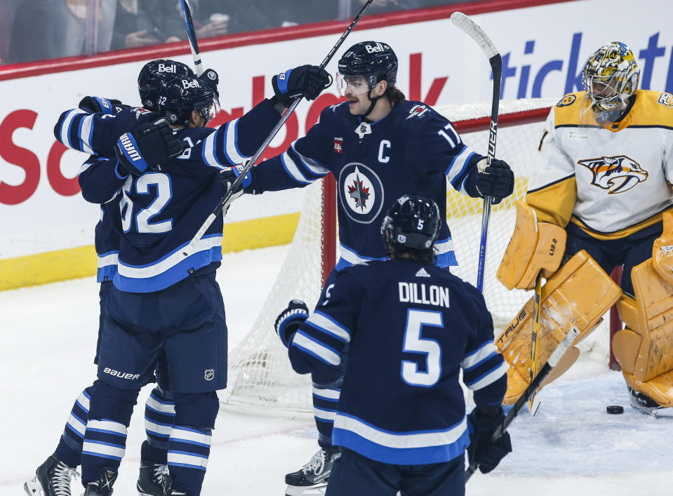 Winnipeg Jets' Mason Appleton (22), Nino Niederreiter (62), Adam Lowry (17) and Brenden Dillon (5) celebrate after Appleton's goal against Nashville Predators goaltender Juuse Saros (74) during first-period NHL hockey game action in Winnipeg, Manitoba, Thursday, Nov. 9, 2023. (John Woods/The Canadian Press via AP)